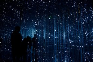 Wide room with lights and mirrors, people standing by watching the futuristic view.